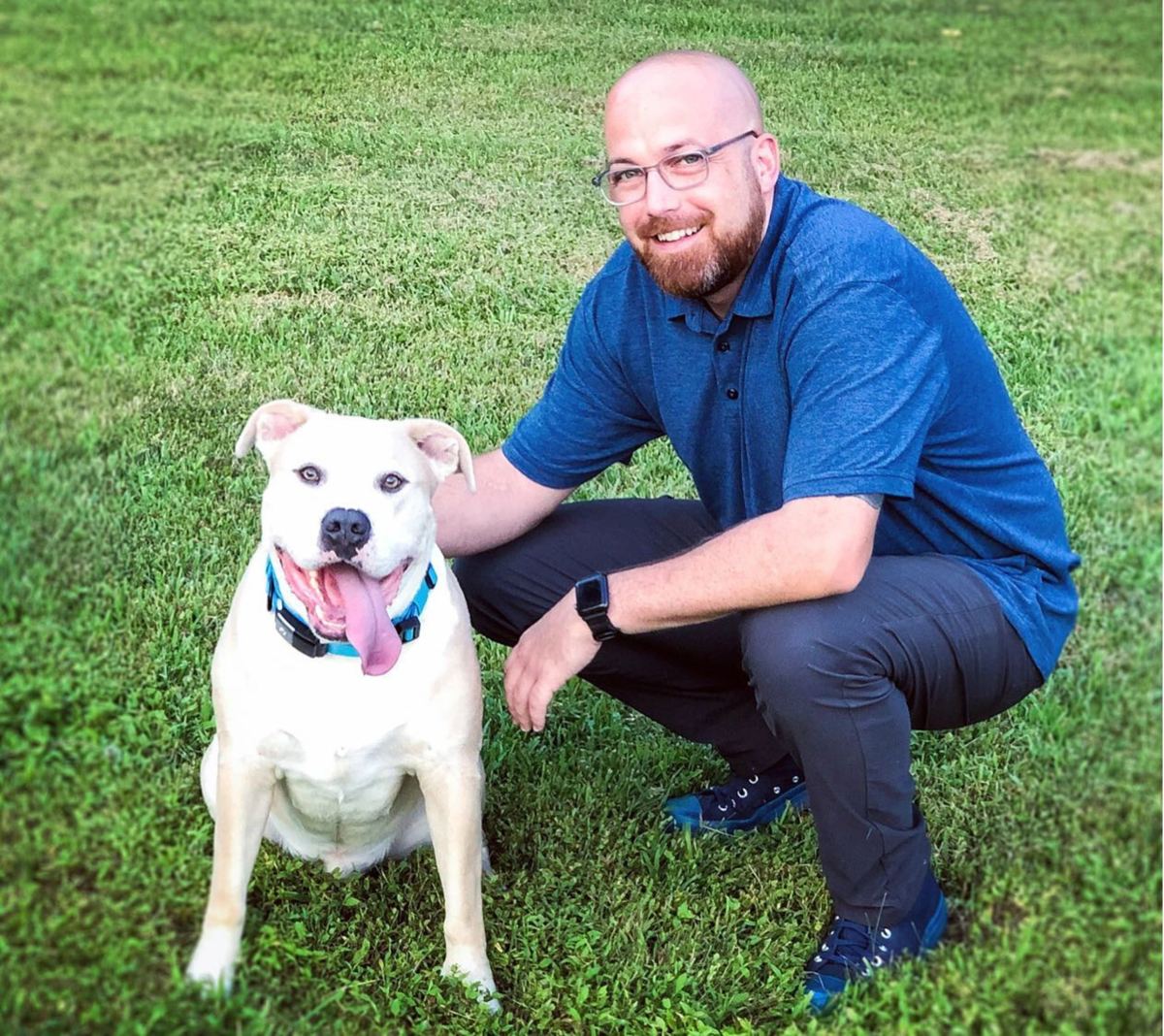 Casey crouching next to a happy white dog on the grass